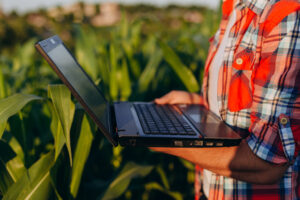 Closeup farmer standing in a field holding open laptop -Image