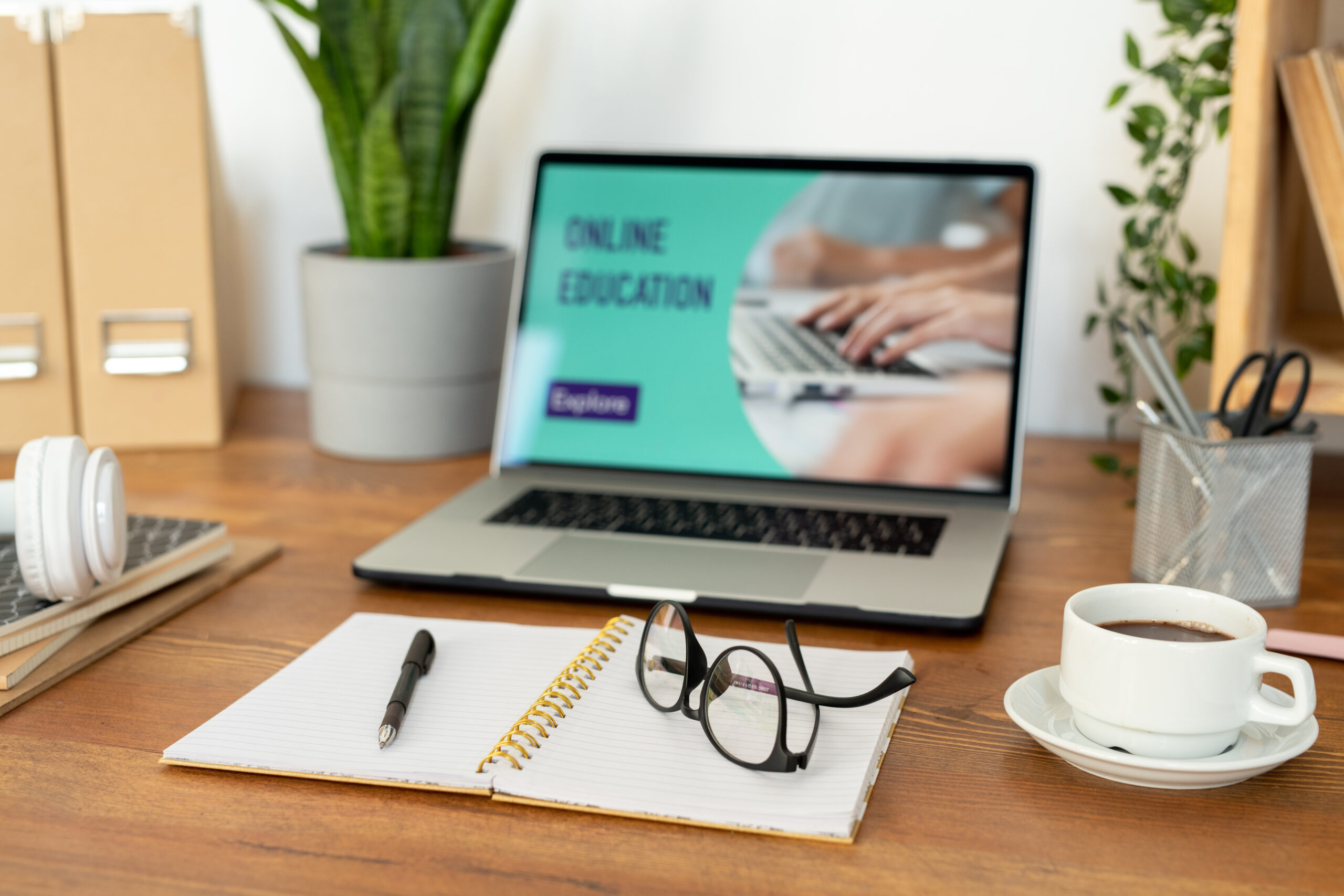 Open notebook with pen and eyeglasses on blank pages and cup of coffee on desk